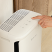 Levoit pet smart air purifier top controls, white unit with hand pressing buttons