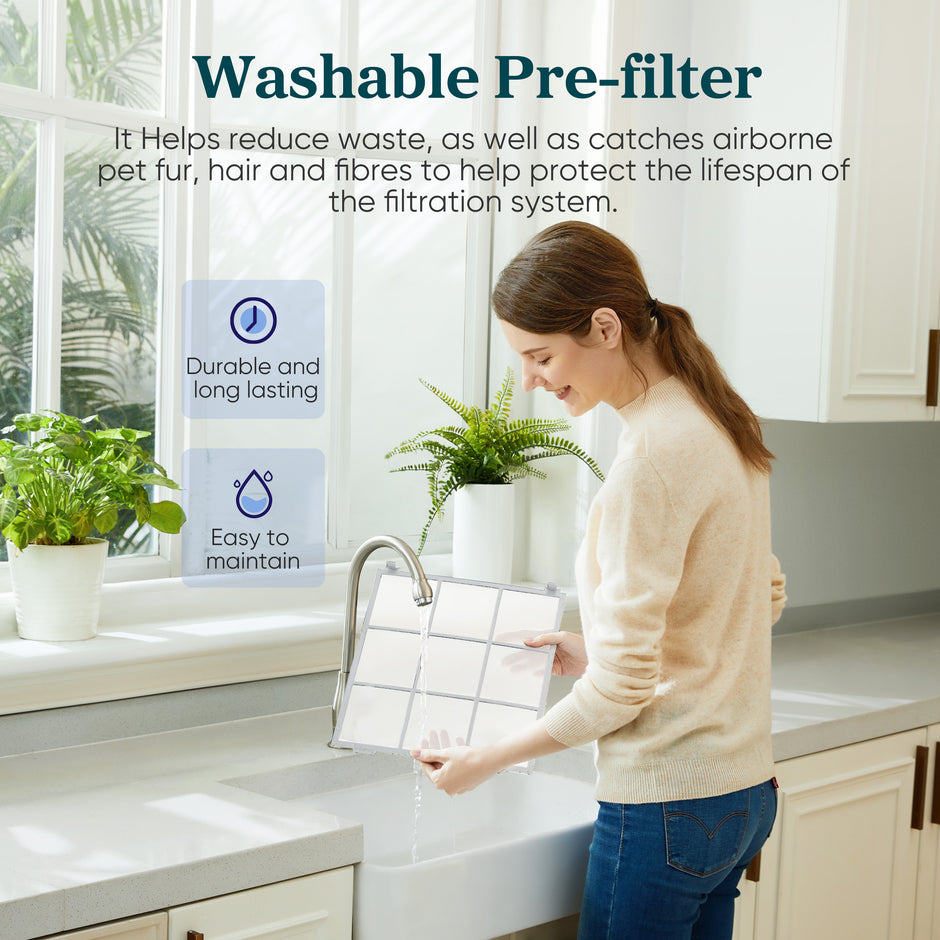 Person holding a washable pre-filter frame next to a white air purifier